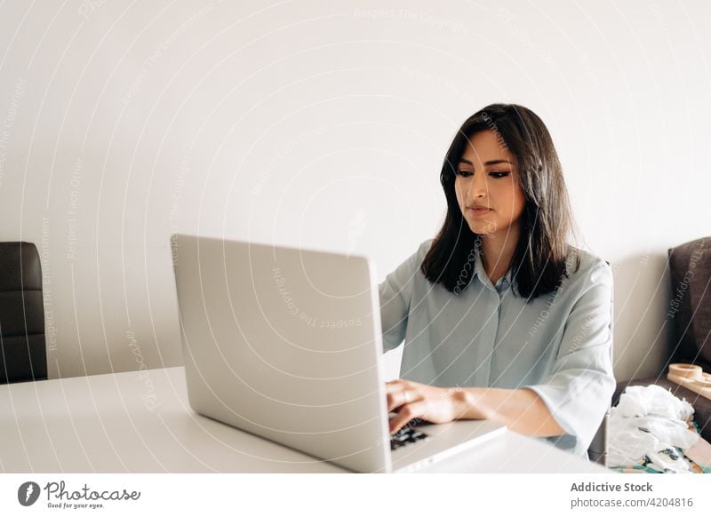Konzentrierte junge Frau arbeitet von zu Hause aus am Laptop Arbeit benutzend abgelegen Konzentration freiberuflich formal Arbeitsbereich Browsen Business Beruf