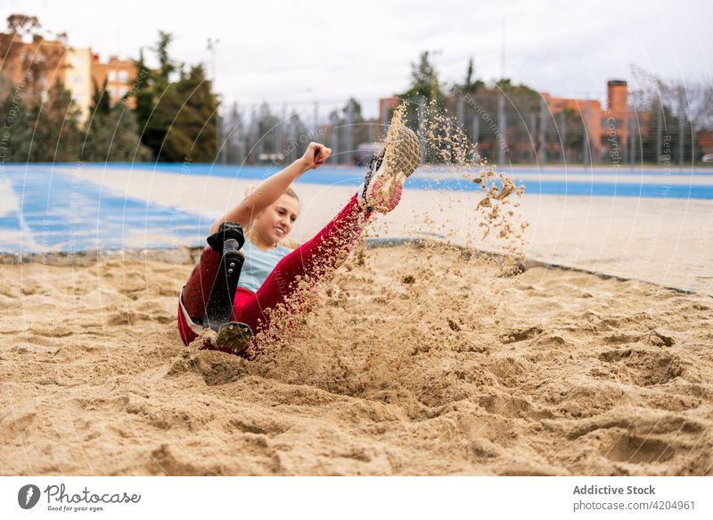 Sportlerin springt beim Training im Stadion in den Sandkasten Prothesen Bein springen Sandgrube paralympisch Athlet Frau Energie Bionik professionell künstlich