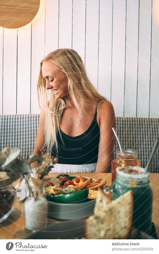 Blonde Frau, die in einem Restaurant sitzt und zur Seite schaut blond trinken Saft Kaukasier Lebensmittel Tisch Sommer Café Mädchen Erwachsener jung Essen