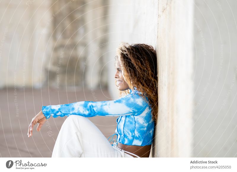 Stilvolle schwarze Frau sitzt in der Nähe eines Gebäudes in der Stadt cool auflehnen Outfit Streetstyle selbstbewusst urban Großstadt trendy ethnisch