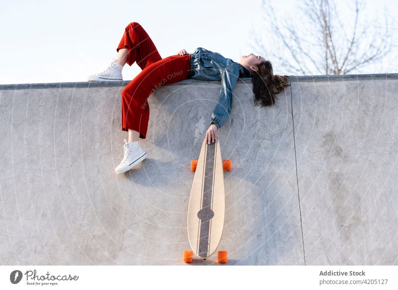 Skateboarder mit Longboard auf der Skateboard-Rampe stehend Frau Skateboarderin ruhen Sport müde erschöpft Himmel Skateplatz urban Sportlerin stylisch wolkig