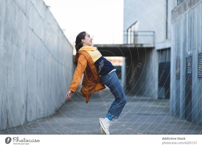 Lächelnder trendiger Teenager auf Zehenspitzen in der Stadt Spaß haben sich zurücklehnen trendy lässig genießen Straße Großstadt Stil cool Inhalt froh Glück
