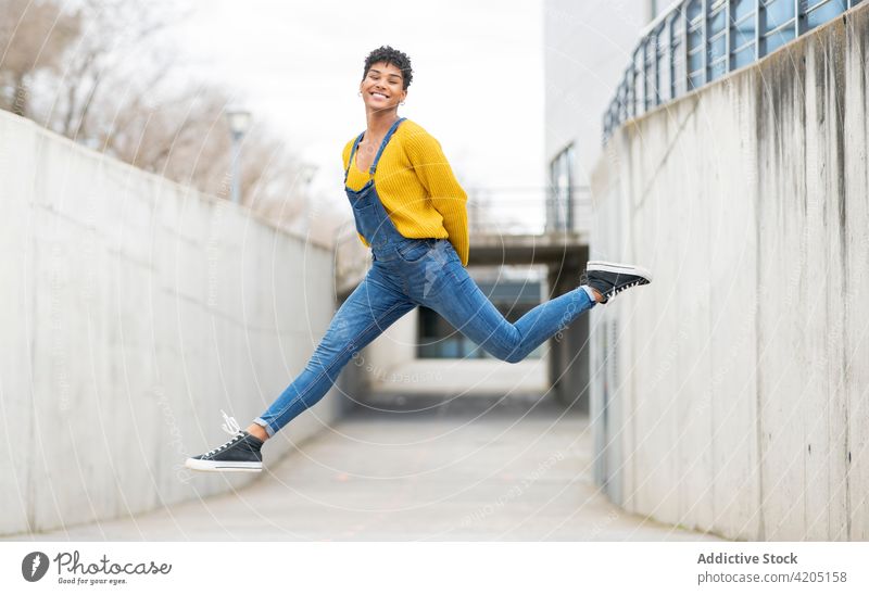 Unbekümmerte schwarze Frau springt in der Stadt über die Straße springen sorgenfrei Moment heiter Freiheit Sprung Großstadt Energie ethnisch Afroamerikaner
