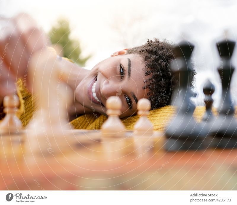 Schwarze Frau spielt Schach im Park spielen heiter Spielfigur Verstand Brettspiel Lächeln ethnisch schwarz Afroamerikaner positiv Tisch froh Freude jung