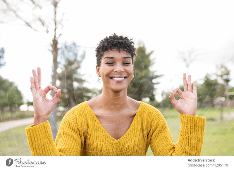 Ethnische Frau zeigt Mudra-Geste im Park Yoga gestikulieren Lächeln Natur Hand Zeichen Harmonie ethnisch schwarz Afroamerikaner Gesundheit Wellness Glück