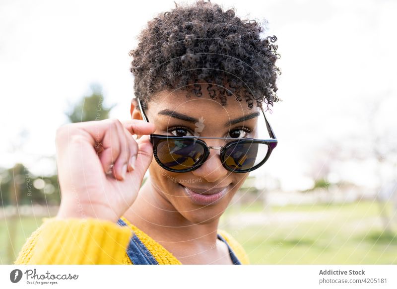 Schwarze Frau mit modischer Sonnenbrille schaut in die Kamera Stil Lächeln Brille trendy Accessoire Afro-Look charmant Vorschein ethnisch schwarz Afroamerikaner
