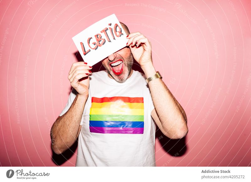 Positive Homosexuell zeigt Papier mit LGBTIQ Aufschrift in rosa Studio Mann Homosexualität schwul Stolz queer lgbt Grimasse Konzept manifestieren Tierhaut
