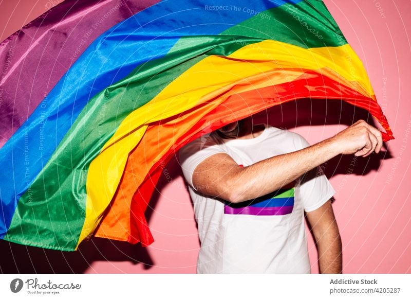 Glücklicher Mann schwenkt LGBT-Flagge in rosa Studio Homosexualität lgbt Fahne schwul Make-up Konzept Stolz Regenbogen gleich männlich unrasiert rote Lippen