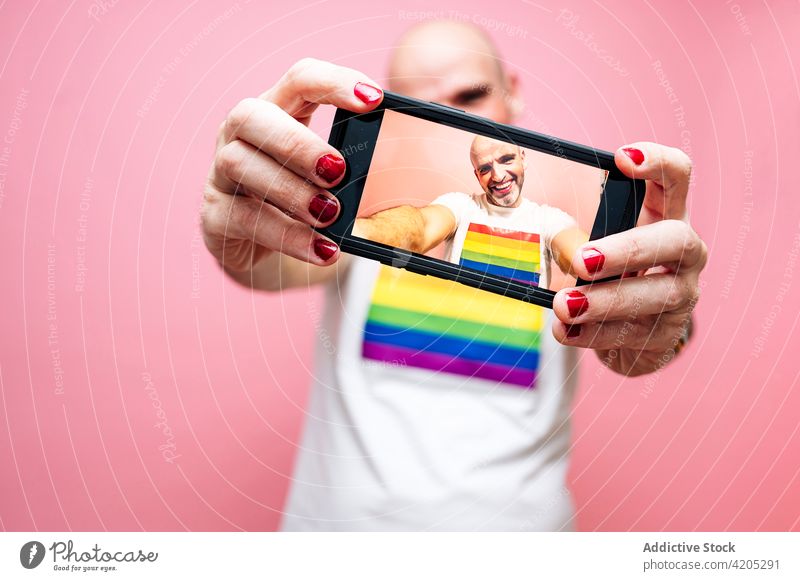 Fröhlicher Mann in Hemd mit LGBT-Flagge macht Selfie mit Smartphone lgbt schwul exzentrisch Lächeln queer Konzept gleich Homosexualität Glück männlich kahl