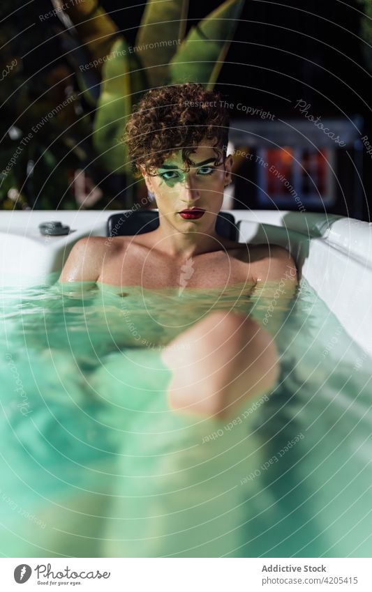 Sinnlicher Homosexueller mit Make-up, der im Whirlpool ruht Mann transsexuell Heißes Bad sinnlich nageln Individualität ungewöhnlich Abenddämmerung Achtsamkeit
