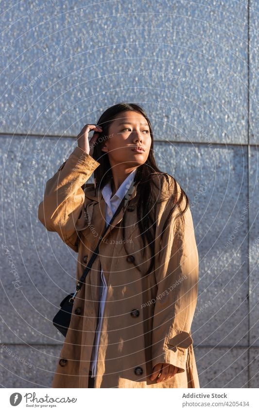Trendige ethnische Frau auf einer Stadtstraße Stil trendy ernst selbstbewusst nachdenklich nachdenken wehmütig Großstadt Straße asiatisch jung dunkles Haar