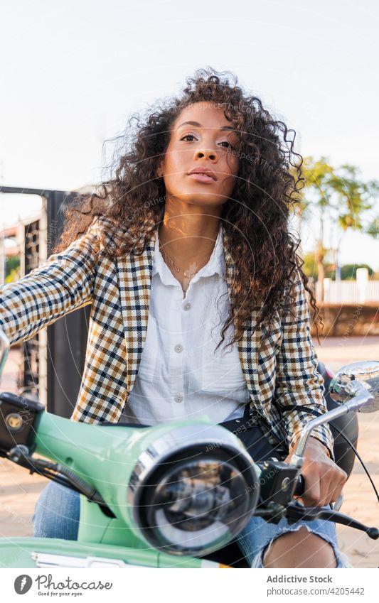 Nachdenkliche ethnische Frau auf Oldtimer-Roller Tretroller wehmütig Verkehr Straße verträumt Großstadt urban nachdenken nachdenklich schwarz Afroamerikaner