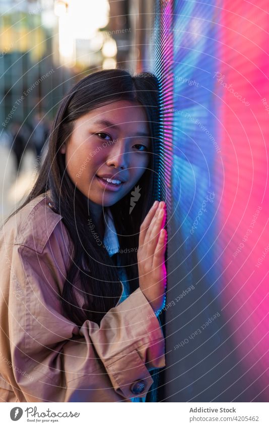 Nachdenkliche Frau in der Nähe von Neonlicht auf der Straße neonfarbig verträumt Stadt Windstille besinnlich nachdenklich Zeichen nachdenken Vorschein