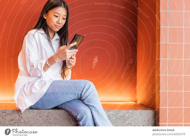 Nachdenkliche asiatische Frau beim Chatten auf dem Smartphone Surfen Browsen Internet benutzend Anschluss Nachricht nachdenklich Windstille Gerät Apparatur