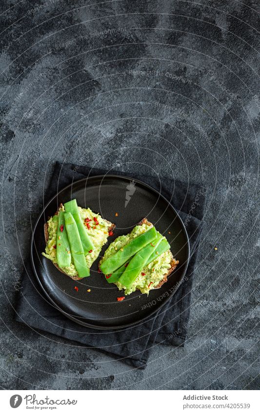 Leckere Toasts mit Guacamole und grünen Erbsenschoten Zuprosten lecker geschmackvoll dienen appetitlich essen Vegetarier Mahlzeit organisch Küche Ernährung