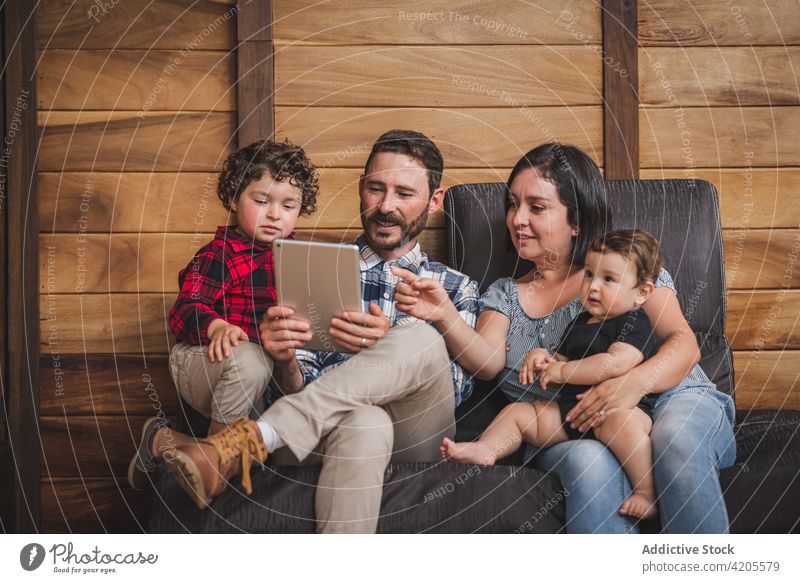Fröhliche Familie, die zu Hause gemeinsam ein Tablet benutzt zuschauen Video Tablette Zusammensein heimwärts heiter Kinder unterhalten Wochenende Apparatur