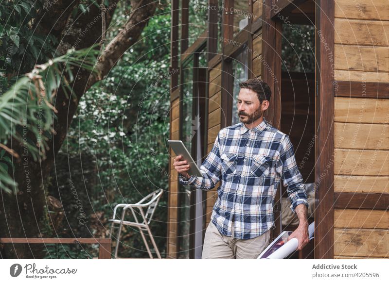 Männlicher Architekt mit Tablet auf der Terrasse eines Hauses Mann Projekt Arbeit Browsen Tablette Bauplan Tiefgang männlich Papier rollen whatman Skizze