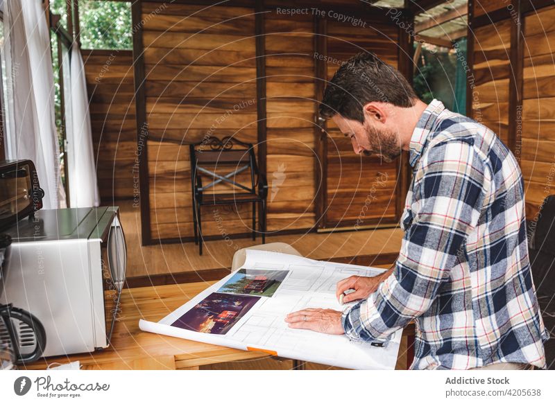 Männlicher Architekt erstellt Entwurf eines Hauses am Tisch Bauplan Mann zeichnen Skizze Projekt Gebäude Papier heimwärts männlich beschäftigt Plan Arbeit