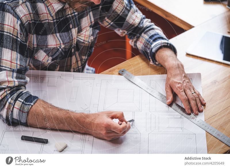 Anonymer Mann zeichnet Entwurf eines Hauses zu Hause Architekt zeichnen Bauplan Skizze Projekt Gebäude beschäftigt Papier männlich Plan heimwärts sitzen Tisch