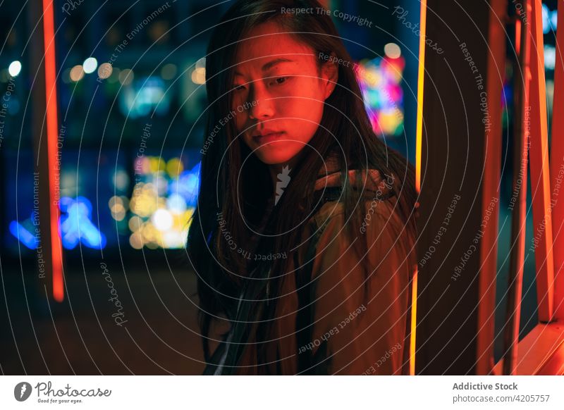 Porträt eines asiatischen Mädchens, das in der Nähe eines roten Neonlichts auf der Straße posiert asiatisches Mädchen Windstille lässig Kälte Chinesisch