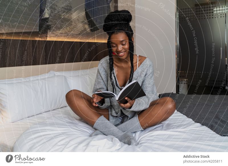 Zufriedene junge schwarze Frau, die auf dem Bett liegend Notizen liest Lügen lesen Buch Schüler Bildung Wissen Anweisung Glück Lächeln positiv Afroamerikaner
