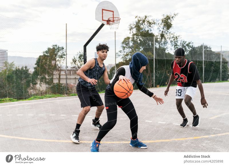 Unterschiedliche Menschen spielen Basketball auf dem Platz Streetball Spieler Zusammensein Team Ball Straße Sportpark rassenübergreifend multiethnisch