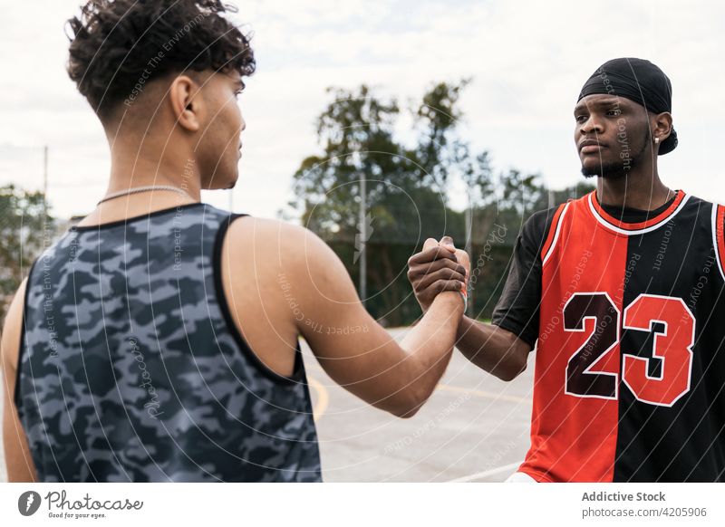 Schwarze männliche Basketballspieler geben sich auf dem Spielfeld die Hand Spieler Hände schütteln Männer Gruß gestikulieren Streetball Gericht Spielplatz