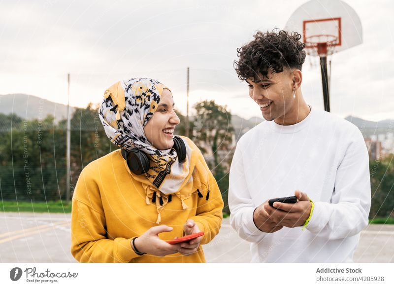 Inhalt: Multirassische Freunde benutzen Smartphones auf dem Basketballplatz Lachen heiter Zusammensein cool Streetstyle Gericht Browsen multiethnisch