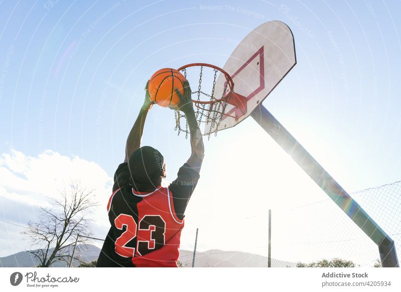 Schwarzer Basketballspieler springt mit Ball auf Spielplatz punkten Mann Spieler Streetball Reifen springen Sportler Moment Energie männlich ethnisch schwarz