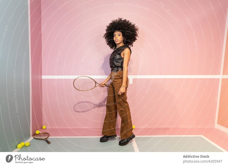 Schwarze Frau mit Tennisschläger im Studio Spieler Gericht Körperhaltung Remmidemmi Mode Atelier trendy Stil Afro-Look selbstbewusst Persönlichkeit