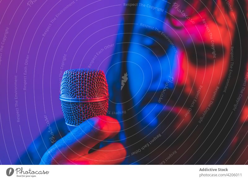 Brutaler Mann singt mit Mikrofon im Neonlicht Sänger Felsen Gesang neonfarbig Hipster Musik Konzert männlich Erwachsener leuchten Klang singen unterhalten