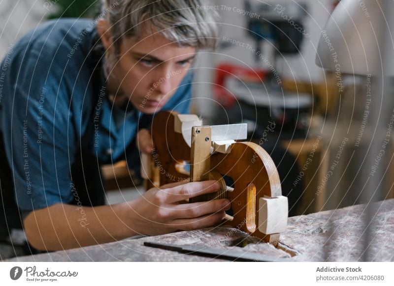 Handwerkerin beim Geigenbau in der Werkstatt schnitzen Ornament Hobelbank Lampe Werkzeug Konzentration handgefertigt Kunstgewerbler Job Beruf professionell