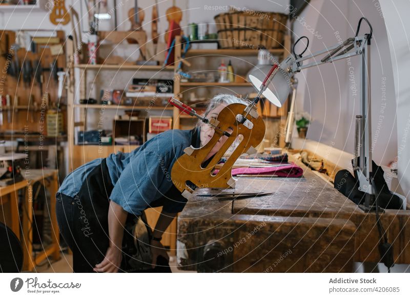 Handwerkerin betrachtet unvollendeten Geigenkörper bewundern unfertig Werkstatt Hobelbank Körperteil einklemmen schäbig professionell Frau Kunstgewerbler Hobby