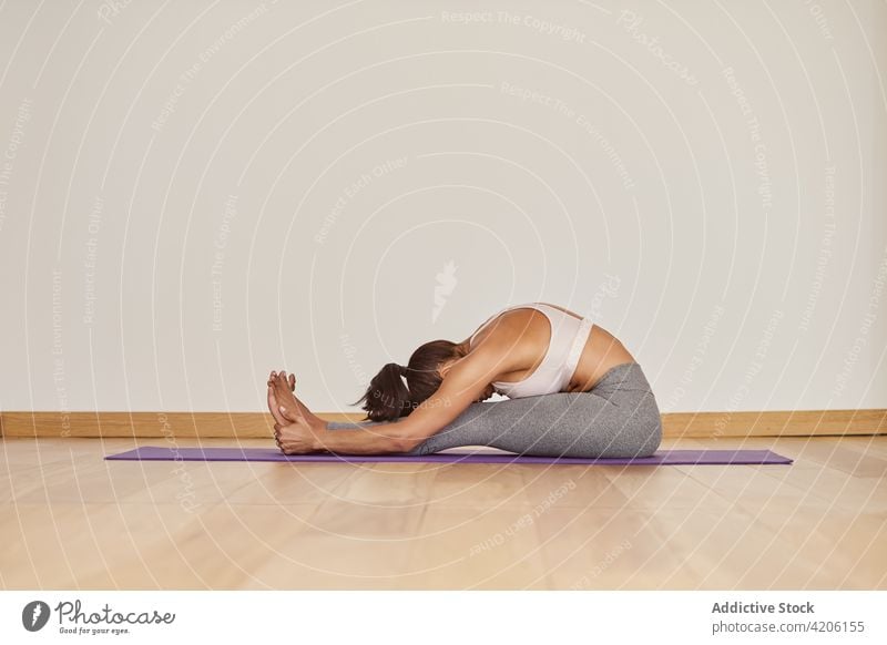 Anonyme Frau zeigt Raupenhaltung auf Yogamatte Raupenpose Dehnung beweglich Gesunder Lebensstil Energie Vitalität Wellness Raum Vorwärtsbeuge Talent Fähigkeit