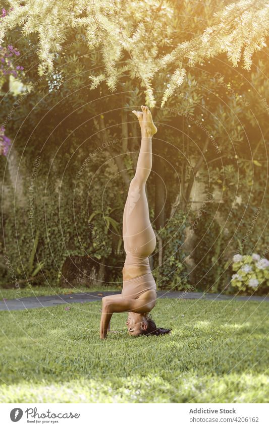 Frau zeigt Handstand-Pose im Park Yoga Gleichgewicht üben Lächeln Dehnung beweglich Wohlbefinden Glück Vitalität Abwärts gerichtete Baumstellung