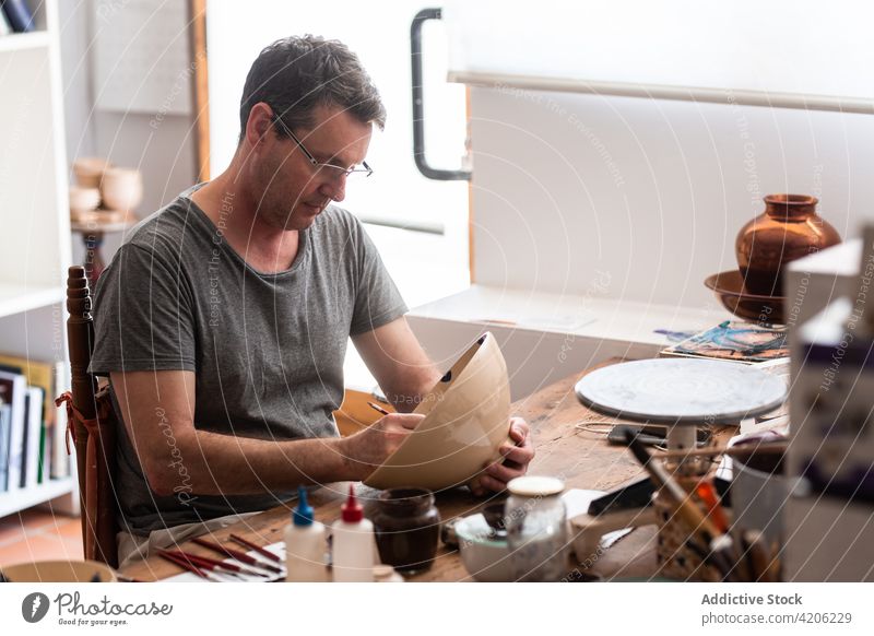 Künstlerzeichnung auf Keramikplatte Mann zeichnen Bürste Handwerk Kunst Werkstatt handgefertigt Hobby männlich Farbe Design Teller Talent Kunstgewerbler