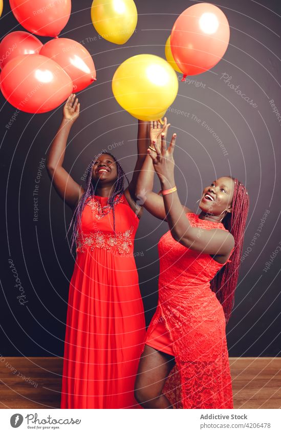 Unbekümmerte schwarze Frauen, die im Studio Luftballons in die Luft werfen feiern festlich heiter Spaß haben Feiertag Veranstaltung ethnisch Afroamerikaner
