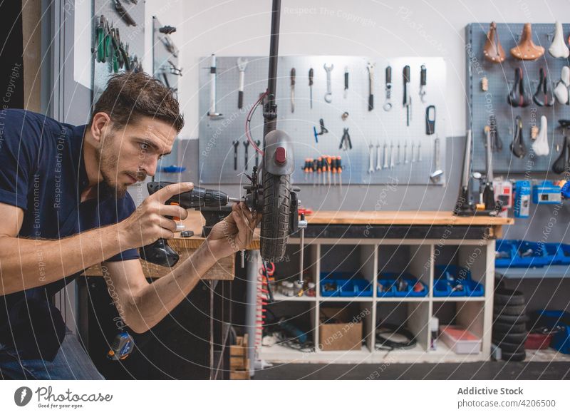 Mechaniker repariert das Rad eines Rollers in der Werkstatt Tretroller Reparatur fixieren Schraubendreher Mann Fahrzeug Dienst Werkzeug Techniker männlich