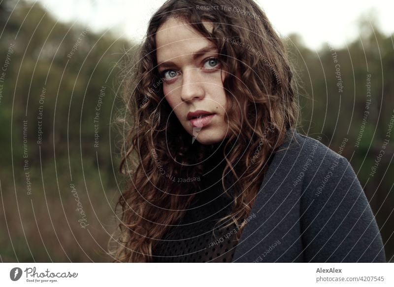 Portrait einer jungen Frau mit langem, brünettem, lockigem Haar vor einer Moorlandschaft junge Frau 18-30 Jahre schön Schönheit Haare lange Haare Locken