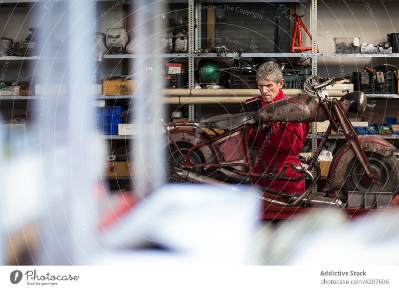Mechaniker repariert altes kaputtes Motorrad in der Werkstatt fixieren versammeln retro altehrwürdig Dienst Mann Fähigkeit Arbeit professionell Reparatur Senior