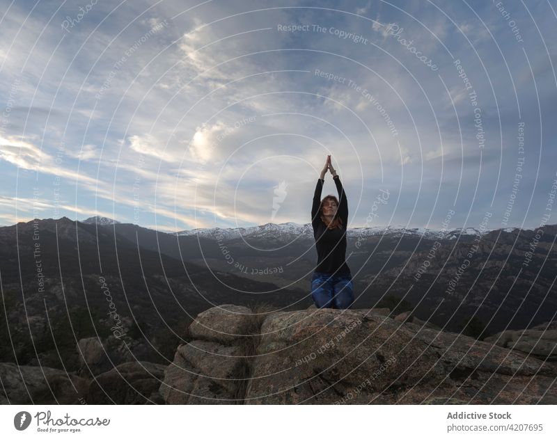 Frau in Donnerkeil-Pose meditiert auf einem Hügel Yoga Sonnenuntergang Donnernde Pose Klippe Augen geschlossen Meditation Arme hochgezogen Vajrasana Vitalität