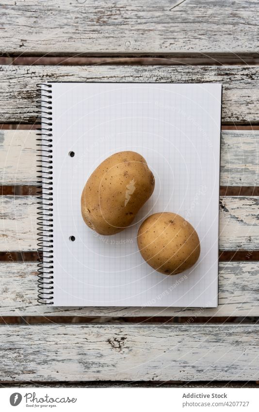 Zwei Kartoffeln auf einem leeren Notizbuch auf dem Tisch Notebook Kraut frisch Grün Notizblock Gesundheit Lebensmittel Schreibtisch Papier Page blanko hölzern