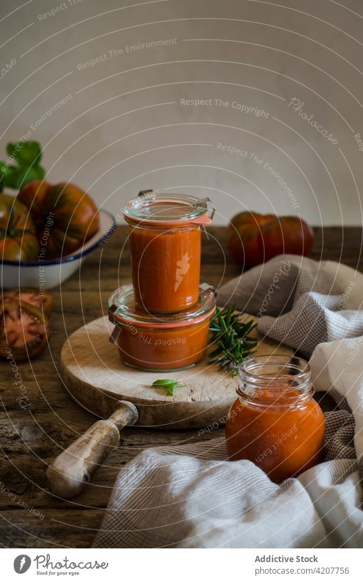Glasgefäße mit hausgemachter gebratener Tomatensauce auf dem Tisch Saucen handgefertigt konservieren frisch Basilikum geschmackvoll Gewürz Küche organisch