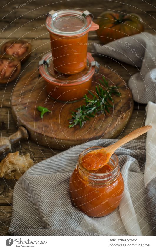 Glasgefäße mit hausgemachter gebratener Tomatensauce auf dem Tisch Saucen handgefertigt konservieren frisch Basilikum geschmackvoll Gewürz Küche organisch