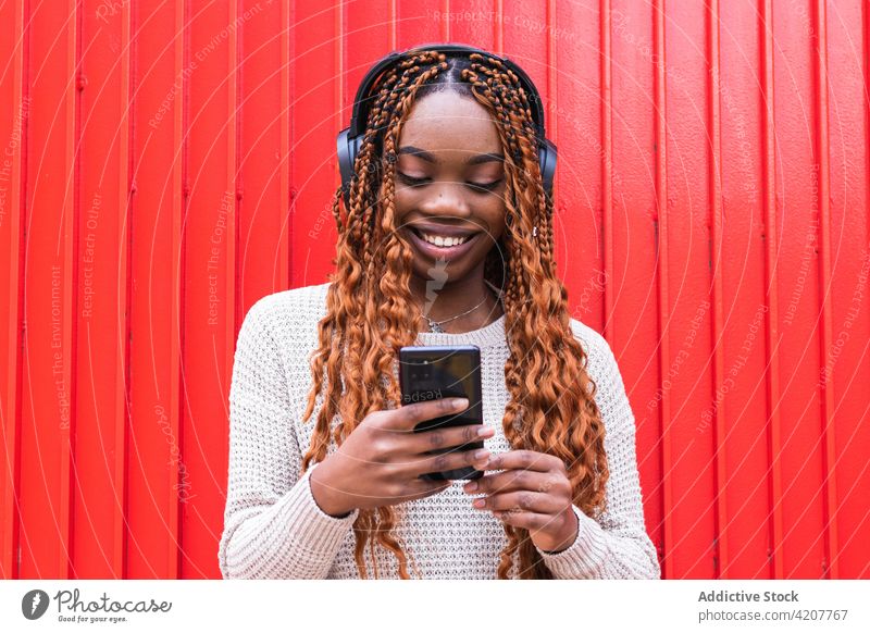 Entzückte schwarze Frau, die mit Kopfhörern Musik hört zuhören genießen sorgenfrei Drahtlos Gesang Lächeln Straße ethnisch Afroamerikaner Gerät Audio