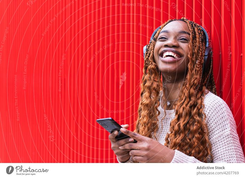 Entzückte schwarze Frau, die mit Kopfhörern Musik hört zuhören genießen sorgenfrei Drahtlos Gesang Lächeln Straße ethnisch Afroamerikaner Gerät Audio Klang