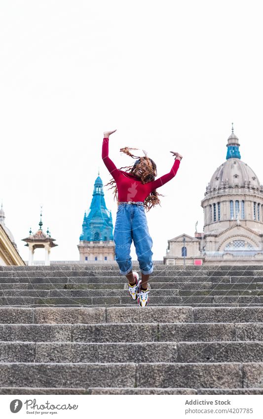 Fröhliche schwarze Frau springt auf einer Treppe in der Stadt springen Moment zuhören Musik Großstadt sorgenfrei heiter Felsen gestikulieren ethnisch