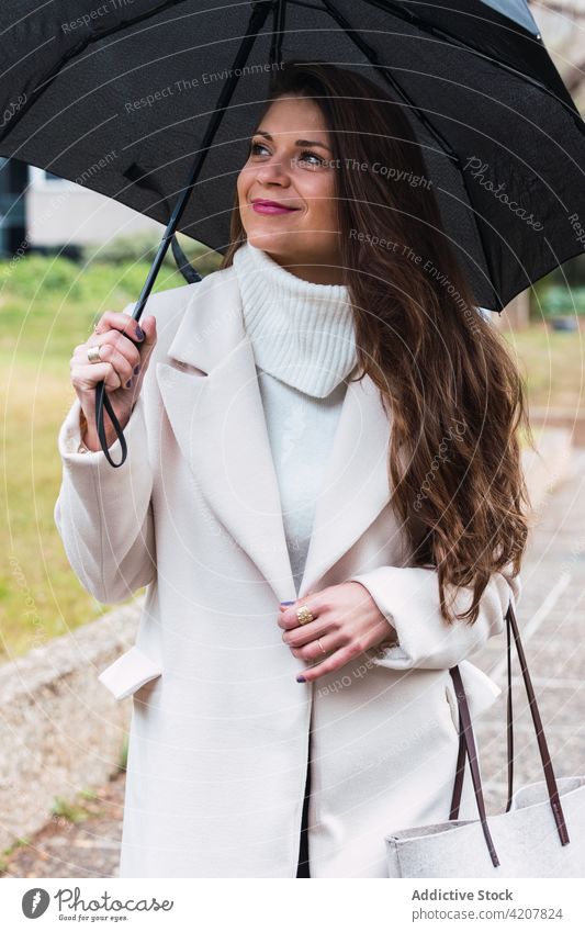 Glückliche stilvolle Frau mit Regenschirm spazieren im Park Mode Frühling Mantel Outfit Stil trendy Erwachsener Accessoire Lifestyle heiter Lächeln Dame