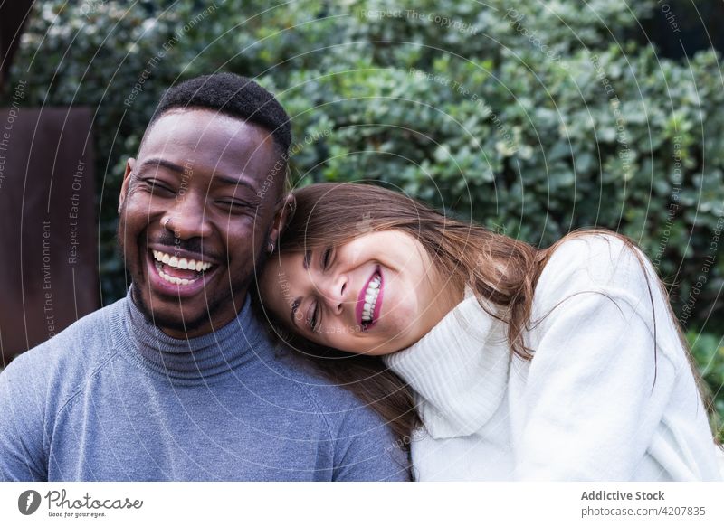 Fröhliches multiethnisches Paar ruht sich im Park aus Liebe romantisch Zusammensein rassenübergreifend heiter Partnerschaft Zuneigung Glück schließen jung