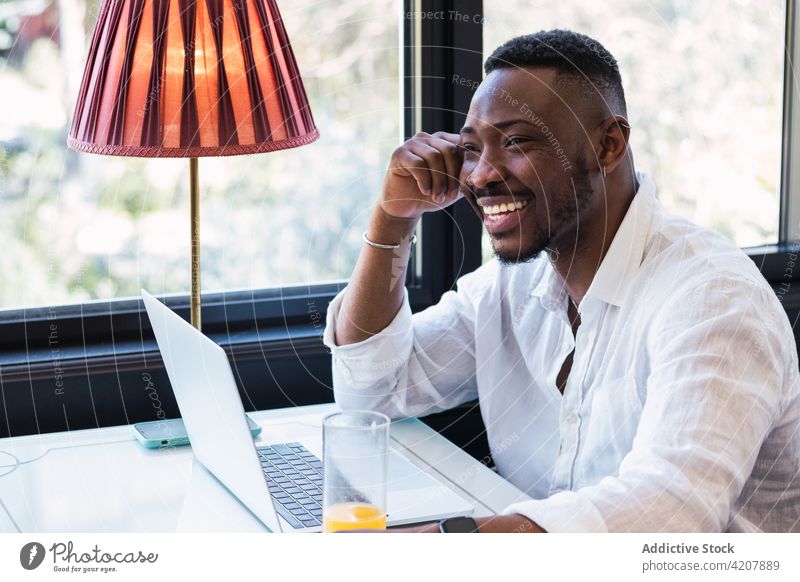 Schwarzer Mann arbeitet in einem Café an einem Laptop benutzend Arbeit abgelegen Browsen digital online freiberuflich beschäftigt Geschäftsmann männlich schwarz
